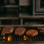 picanha, tri-tip, lamb shoulder, pork coppa, and short ribs cooking over a grill at a restaurant